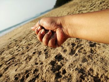 Close-up of hand on sand at beach