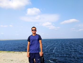 Young man standing in sea against sky
