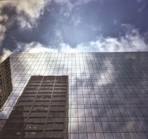 Low angle view of modern building against cloudy sky