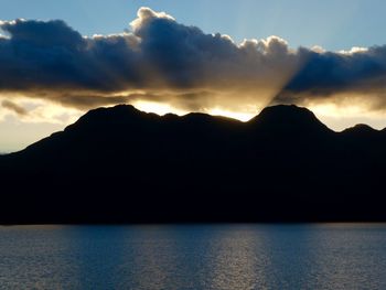 Scenic view of silhouette mountain by sea against sky during sunset