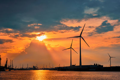 Silhouette cranes against sky during sunset