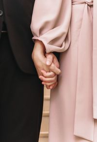 Midsection of couple holding hands