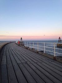 Pier over sea against clear sky during sunset