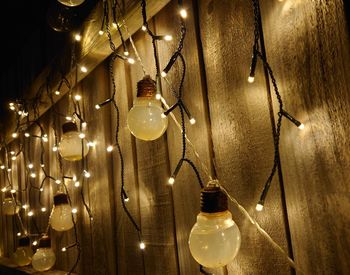 Close-up of illuminated light bulb hanging from ceiling