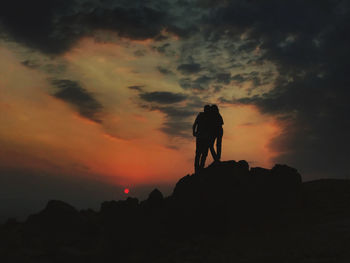 Silhouette man standing on mountain against sky during sunset