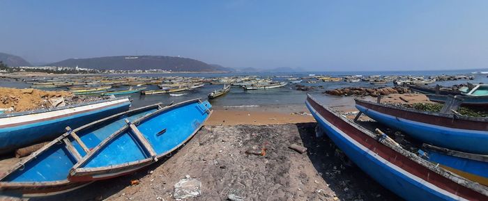 Boats moored on sea against clear blue sky