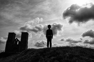 Rear view of man standing on field against sky