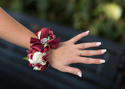 Cropped hand of woman wearing flower bracelet outdoors