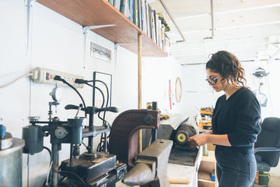 Wide shot of women working using precise tool to make a small product