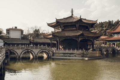 Arch bridge over lake against old temple in city