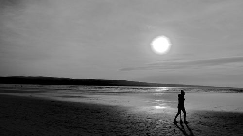 Silhouette woman standing on beach against sky