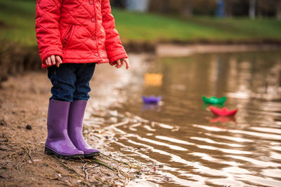 Low section of girl with pink umbrella on water