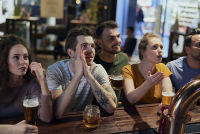 Happy friends watching soccer match at bar