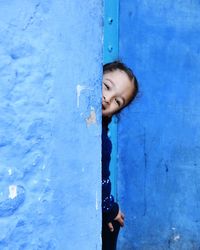 Portrait of happy woman against blue wall