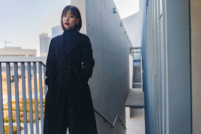 Portrait of woman standing by wall