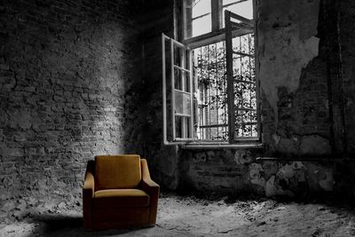 Abandoned chair against wall in old building