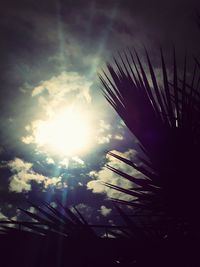 Low angle view of sun shining through clouds