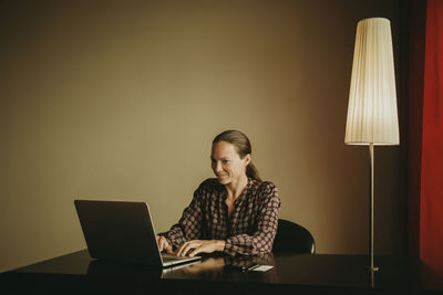 Full length of woman sitting on table at home