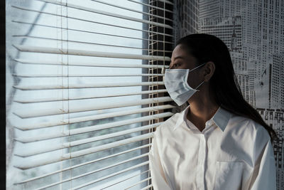 Portrait of woman standing against window