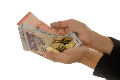 Close-up of hand holding coins against white background