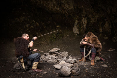 Warriors with weapon sitting on rock in forest