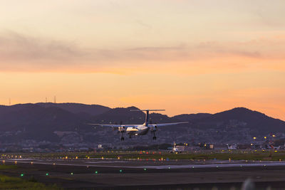 Airplane on airport runway against sky during sunset