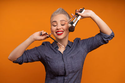 Full length of young woman standing against orange background