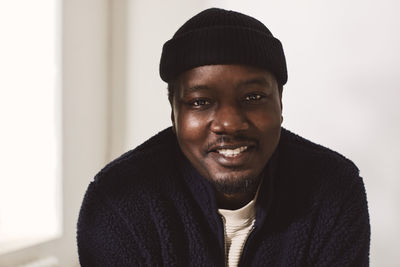 Smiling mid adult man wearing knit hat against wall