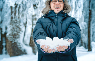 Man with snow in hands in winter forest