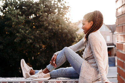 Happy mature woman sitting on wall at terrace