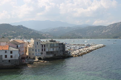 Scenic view of sea by townscape against sky