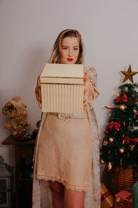 Portrait of teenage girl standing in front of christmas tree