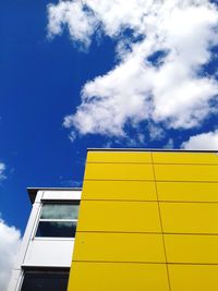 Low angle view of yellow building against cloudy sky