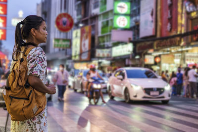 Side view of woman standing in city