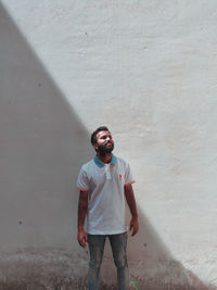 Portrait of young man standing against wall