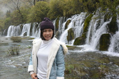 Portrait of smiling woman standing against river