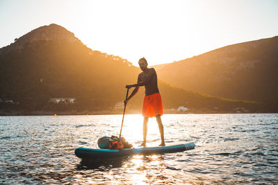 Full length of man standing on paddleboard in lake