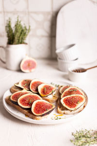 Breakfast with sweet bruschettas with figs and honey on a white plate