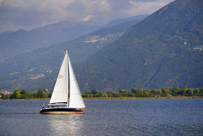 Sailboat sailing on sea against mountains