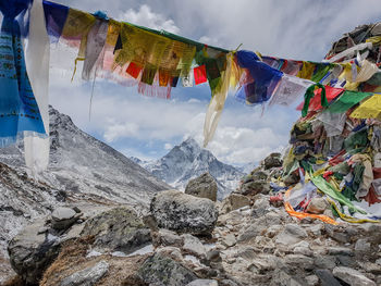 Low angle view of prayer flags hanging on mountain against cloudy sky