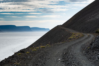 Scenic view of road by mountains against sky