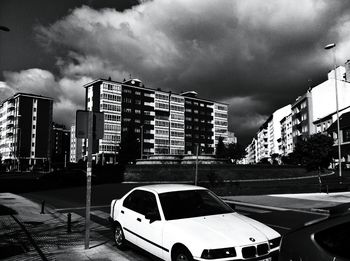 Cars on road by buildings against sky in city