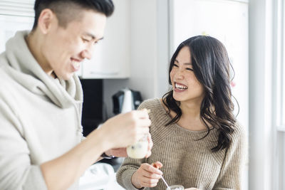 Cheerful couple eating breakfast in kitchen