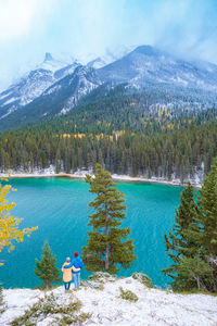 Rear view of person looking at lake by mountain against sky