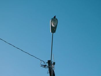 Low angle view of telephone pole against clear blue sky