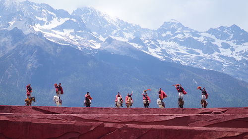 Group of people on snowcapped mountain against sky