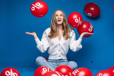 Woman with red balloons against blue background