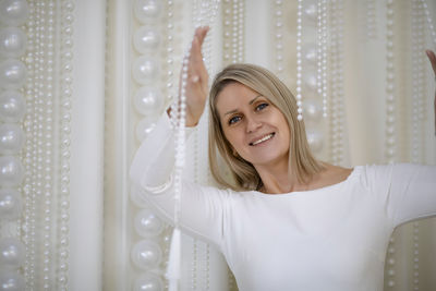 Portrait of young woman standing against curtain