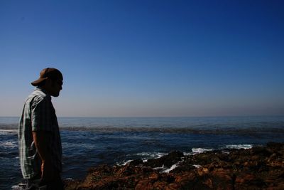 Side view of woman standing at beach against sky