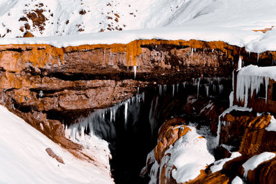 Panoramic view of frozen rock formation by snowcapped mountains